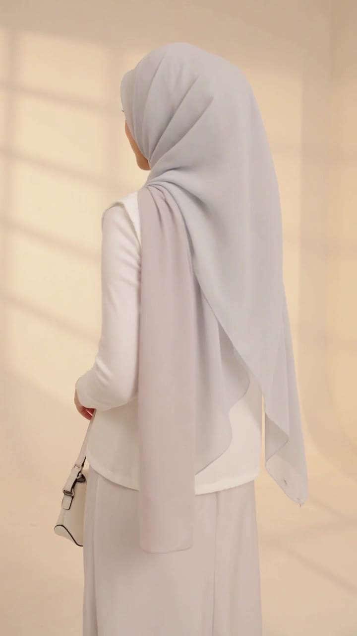 Lydia Farida walking away through a gold-lit hotel corridor in a navy hijab